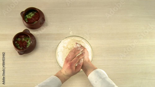 Cooker stirring dough in glass bowl top view photo