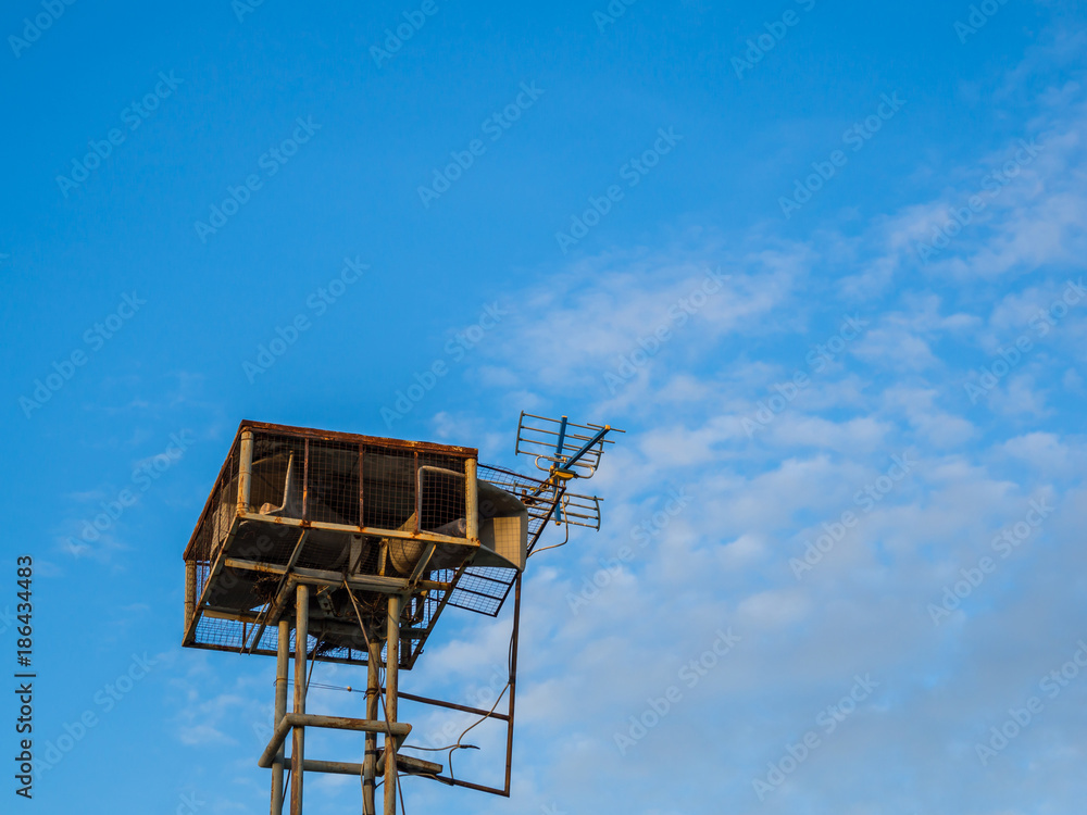 Old public loudspeakers broadcast vintage style on high tower the blue sky background