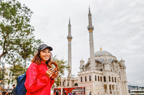 Obraz na płótnie Young woman eating turkish bagel in Istanbul, Turkey on the background of Ortakoy mosque w salonie