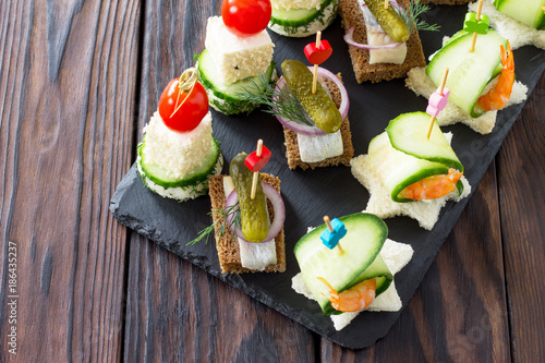 Canape with royal prawns, raw feta and herring on black bread on a slate board. Valentine's Day or wedding.
