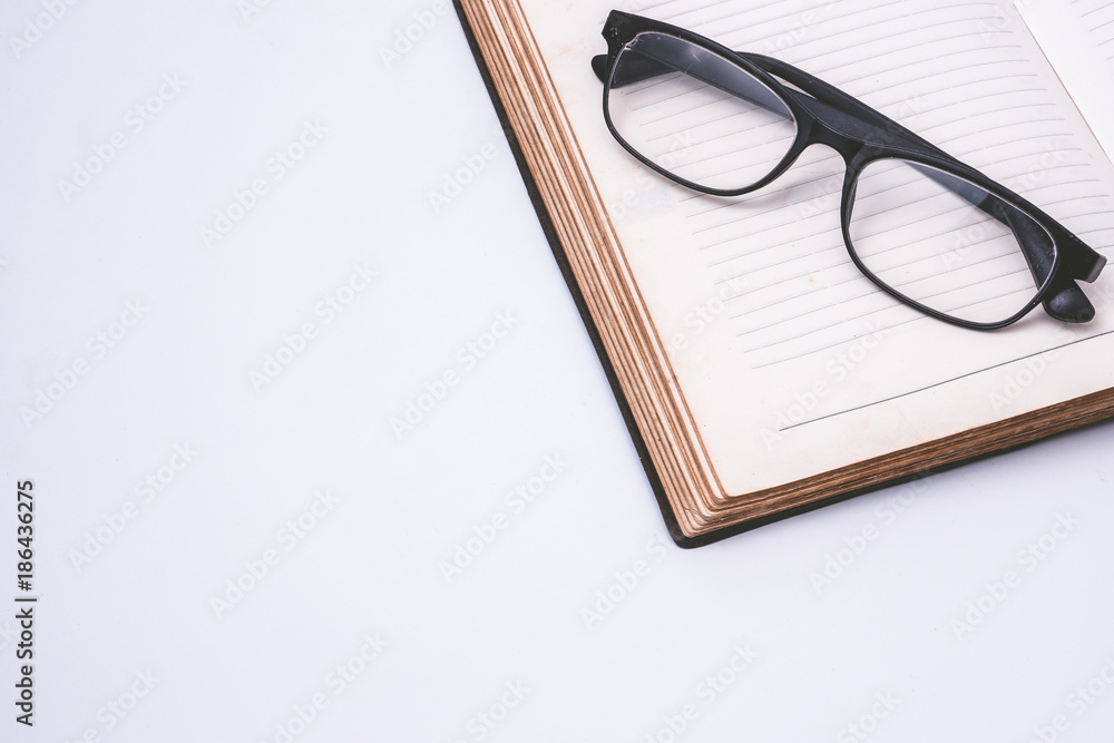An open notebook with glasses on white background. Free space for text An open notebook with glasses on white background. Free space for text