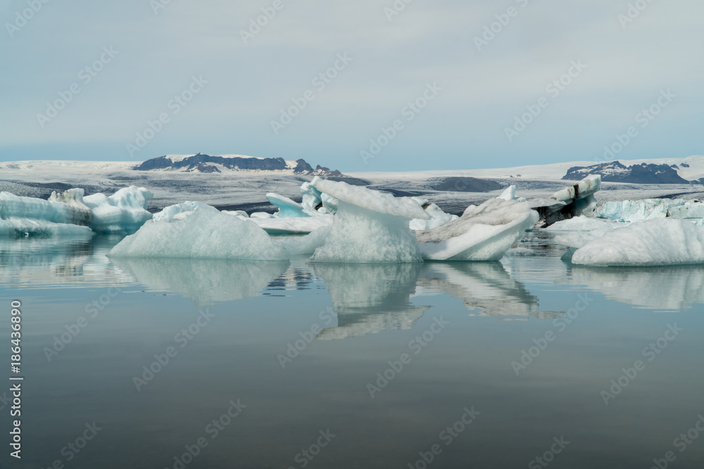 Jokulsarlon glacier lagoon bay with blue icebergs floating on still water with reflections, Iceland