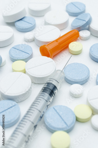 colorful tablet and disposable syringe on white background, closeup