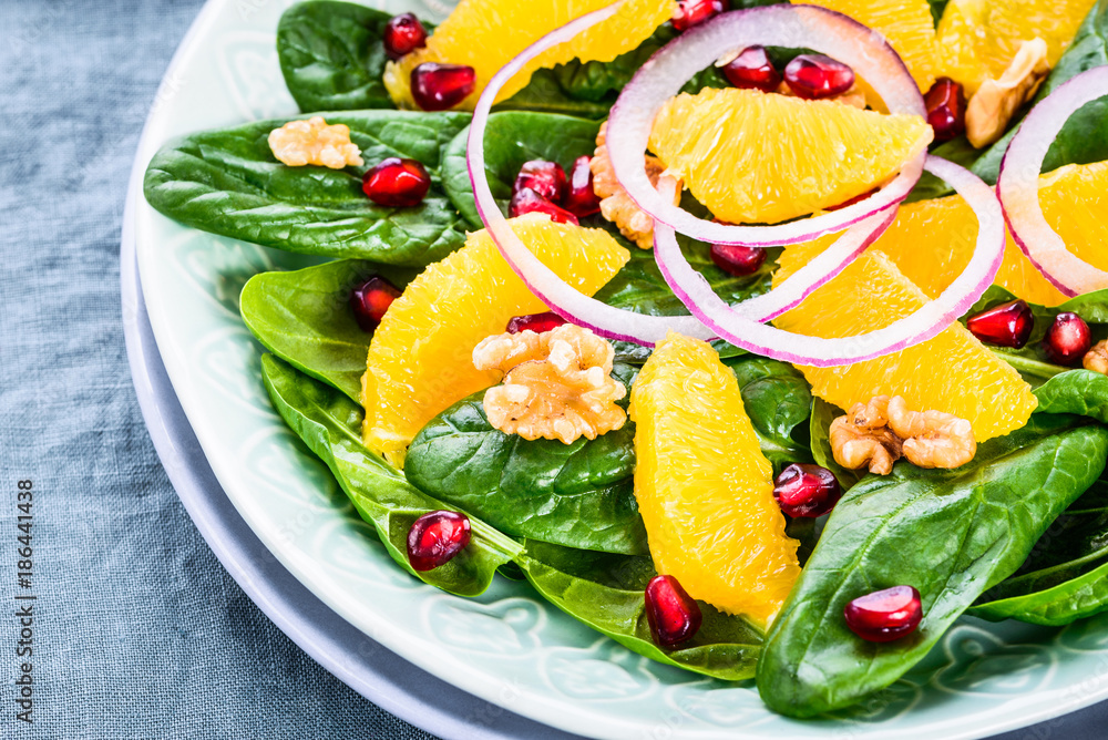 Spinach salad with orange pomegranate and nuts.Light healthy vitamin salad bowl. Spinach salad with orange pomegranate and nuts.Light healthy vitamin salad bowl.