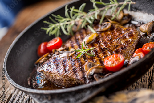 Beef steak. Grill beef flank steak with rosemary musrooms and tomatoes in pan photo