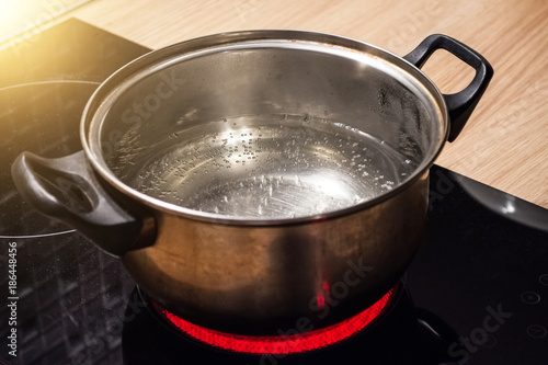 Obraz na plátne Metal pan with boiling water on the induction cooker red hot plate