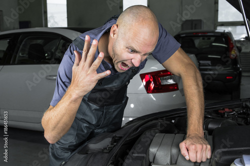 Young car service technician who repair the car engine motor.