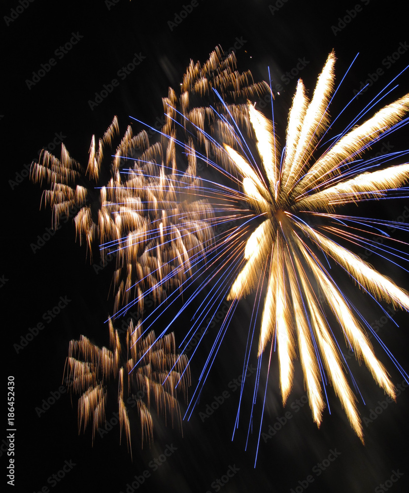 photo of yellow and blue explosions of fireworks on New Year celebration - obrazy, fototapety, plakaty 