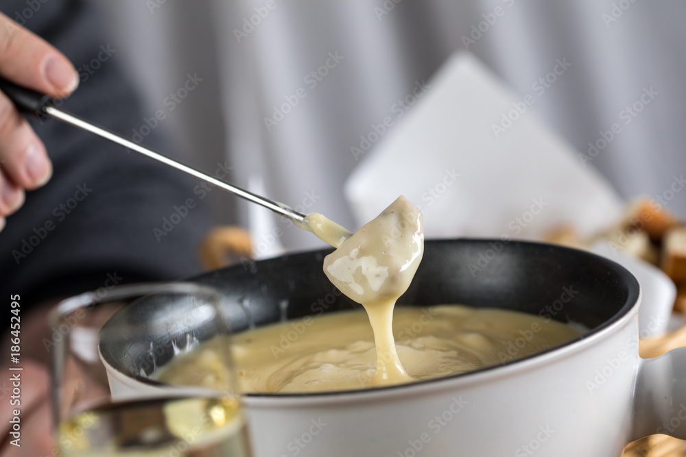 Mann isst klassisches Käse Fondue mit Brot und Sekt Mann isst klassisches Käse Fondue mit Brot und Sekt