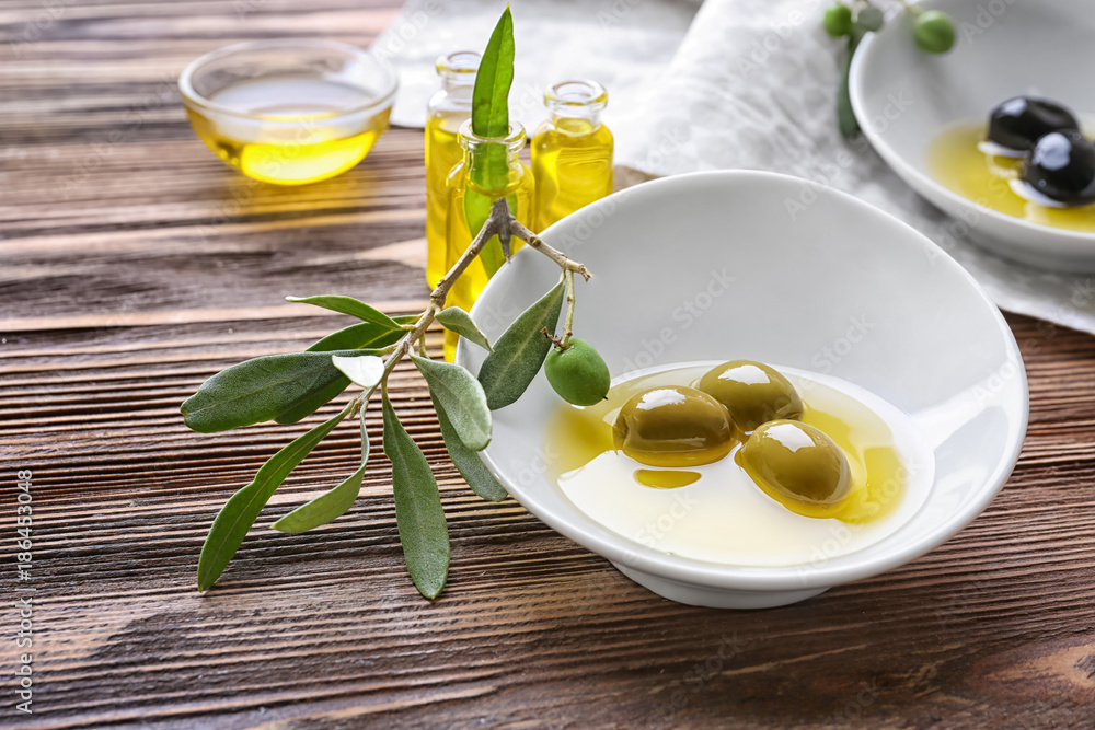 Bowl with olive oil on wooden table Bowl with olive oil on wooden table
