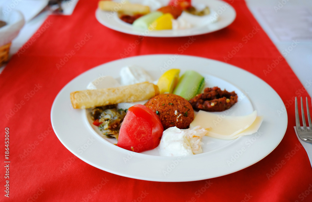 Plate of delicious appetizer with cutlet, cheese, vegetables and sauces on table Plate of delicious appetizer with cutlet, cheese, vegetables and sauces on table