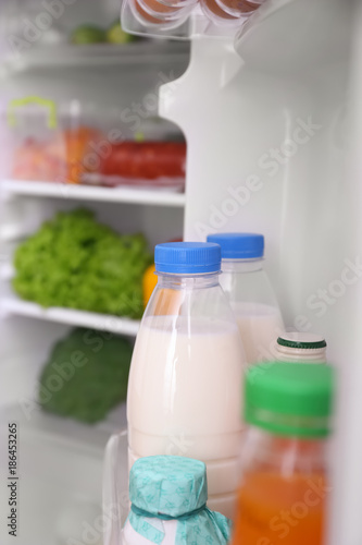 Bottles with milk on refrigerator shelf, closeup