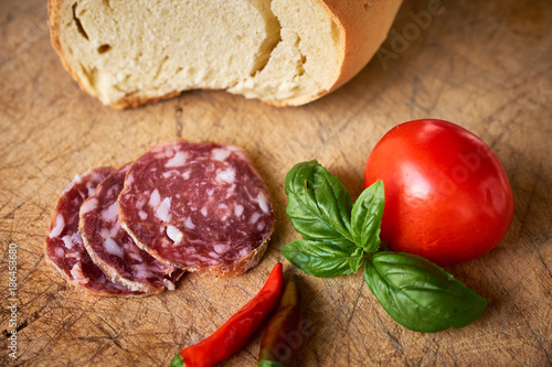 Pane siciliano, salame affettato, pomodoro e basilico su tagliere