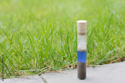 Checking the ph value of garden soil with a simple ph metre. Soil and reagent liquid in a glass test tube. glass tube with plug on it. Blue color showing neutral ph value.