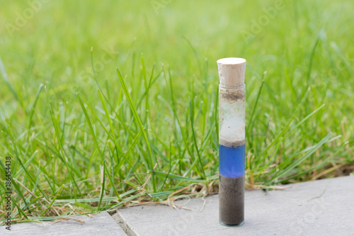 Checking the ph value of garden soil with a simple ph metre. Soil and reagent liquid in a glass test tube. glass tube with plug on it. Blue color showing neutral ph value. photo