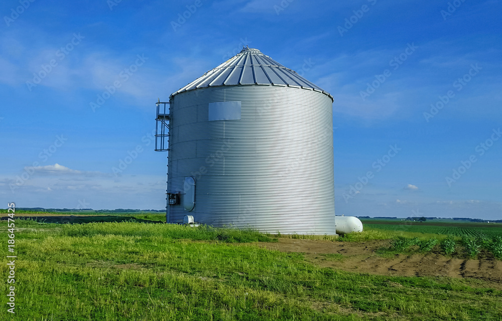 Metal silo on farmland in Central Illinois. Blue sky in the background.