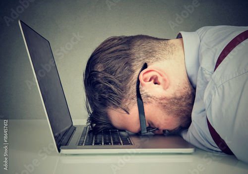 Overworked man lying on laptop photo