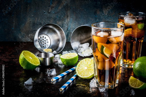 Cuba Libre, long island or iced tea cocktail with strong alcohol, cola, lime and ice, two glass, dark background copy space