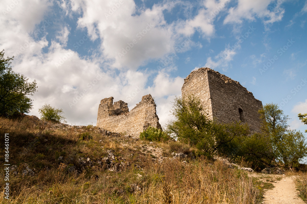 ruins on top of hill with blue sky and white clouds in background