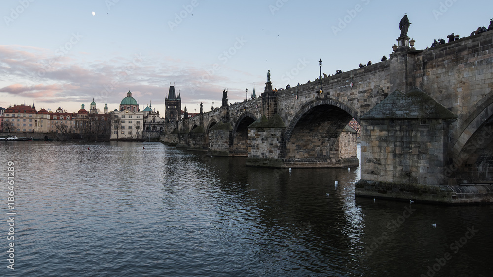 View of 14th century Charles bridge and old Town Prague across the Vltava (Moldau) river. Picture taken from left bank on late afternoon in winter.