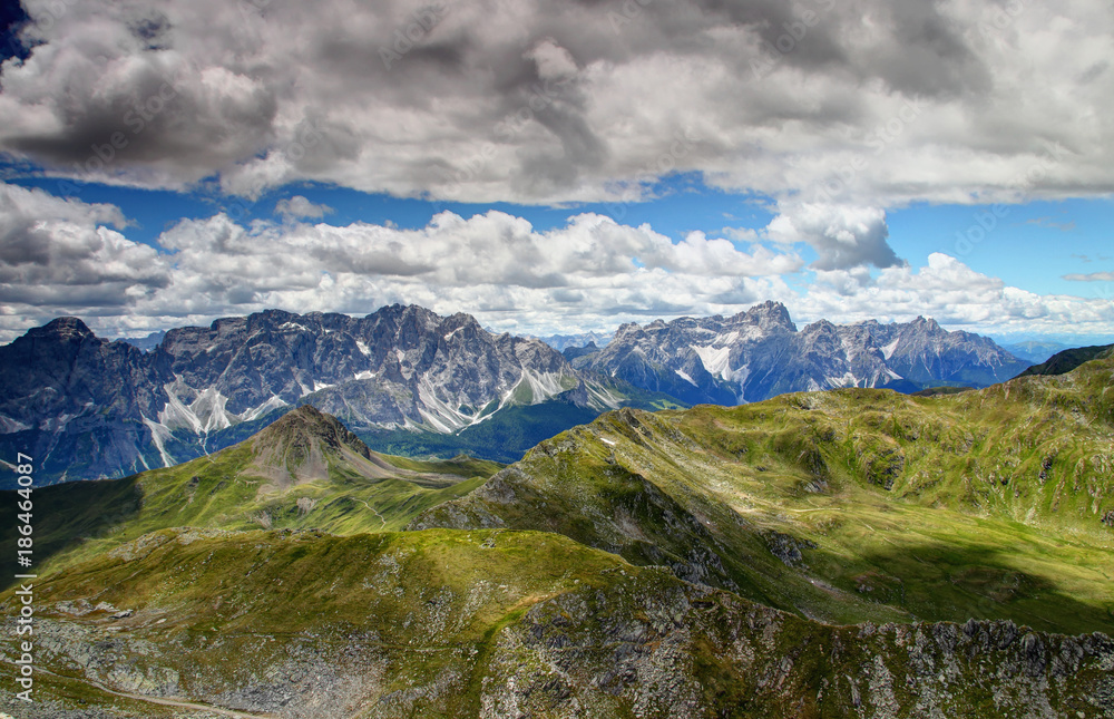 Gentle green slopes of Carnic Alps and  jagged rock faces Sexten Dolomites with Monte Popera, Cima Undici, Croda Rossa di Sesto and Punta dei Tre Scarperi peaks, Belluno and South Tyrol, Italy, Europe