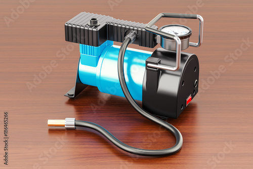 Car portable electric air compressor on the wooden table. 3D rendering photo