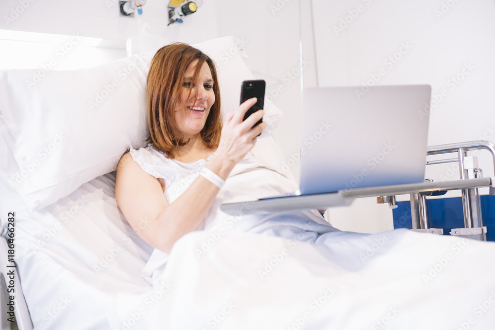 ill woman with Smartphone and laptop in the hospital ill woman with Smartphone and laptop in the hospital