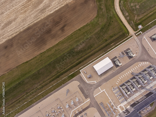 Aerial view over modern power plant, transformer station surrounded with agriculture fields in Alytus, Lithuania. During cloudy early summer day. photo