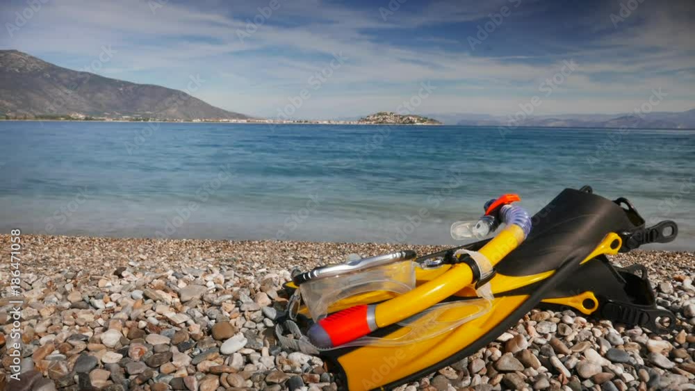 Snorkel equipment flippers and snorkeling mask tube lying on stone beach sea shore. Greece paralio Astros Peloponnese. Summer vacation swimming fun concept. Timelapse 4K Snorkel equipment flippers and snorkeling mask tube lying on stone beach sea shore. Greece paralio Astros Peloponnese. Summer vacation swimming fun concept. Timelapse 4K