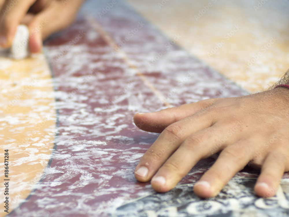 Surfer rubs the wax into the board Surfer rubs the wax into the board