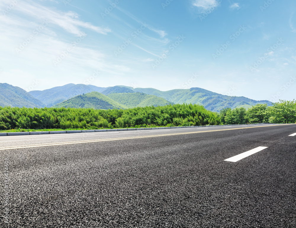 Fototapeta premium country road and mountains with forest in summer