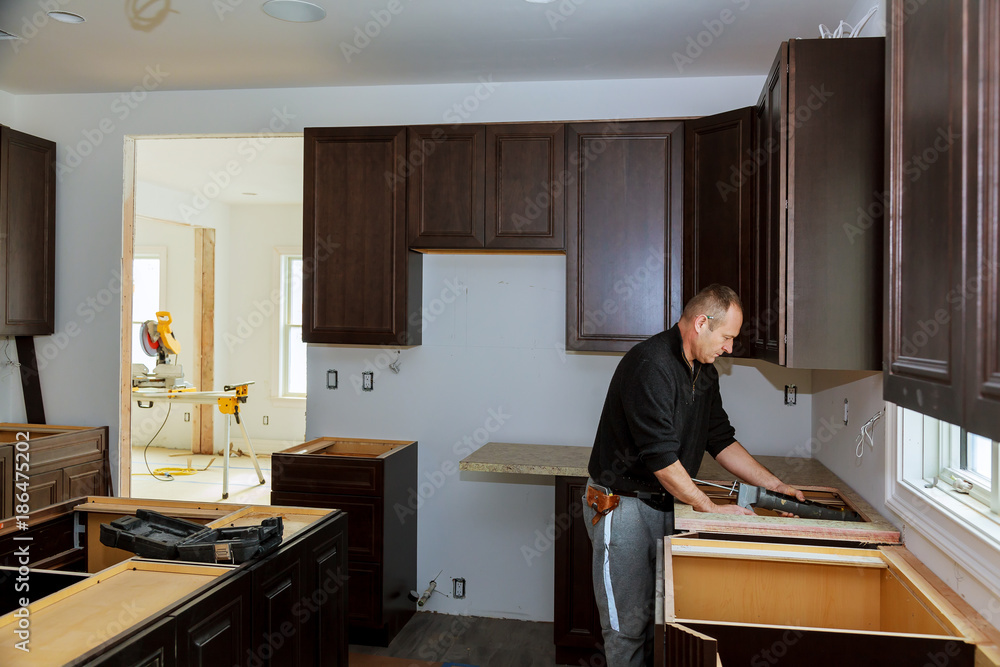 Carpenter installing cabinets and counter top in a kitchen. and partially installed Carpenter installing cabinets and counter top in a kitchen. and partially installed