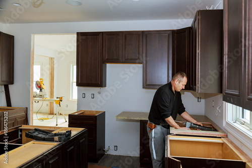 Carpenter installing cabinets and counter top in a kitchen. and partially installed