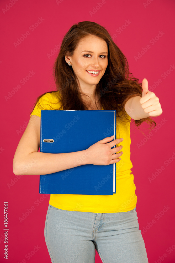 attractive young student in yellow t shirt holding red folder over pink background attractive young student in yellow t shirt holding red folder over pink background