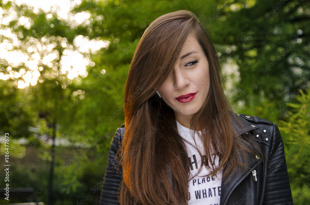 Portrait of Gorgeous long hair woman in park in leather jacket Portrait of Gorgeous long hair woman in park in leather jacket