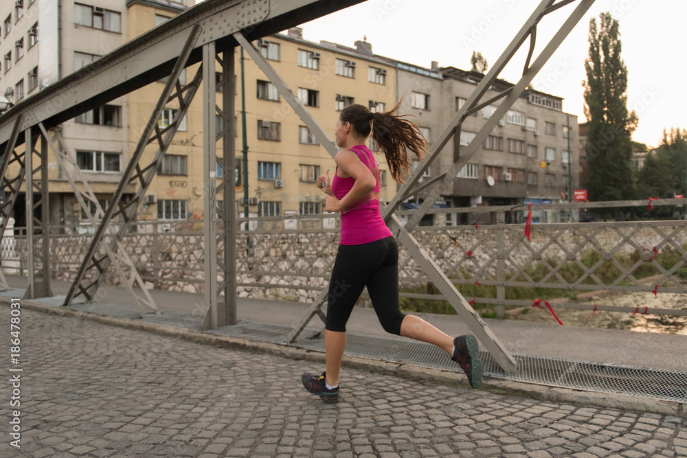 woman jogging across the bridge at sunny morning woman jogging across the bridge at sunny morning