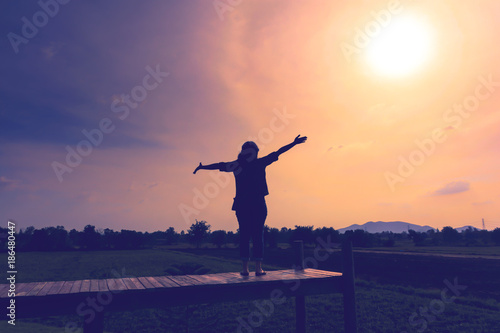 A happy woman stand arms to see the sun.