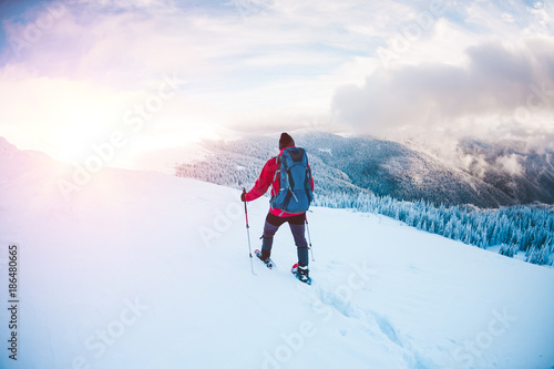 A man in snowshoes in the mountains.