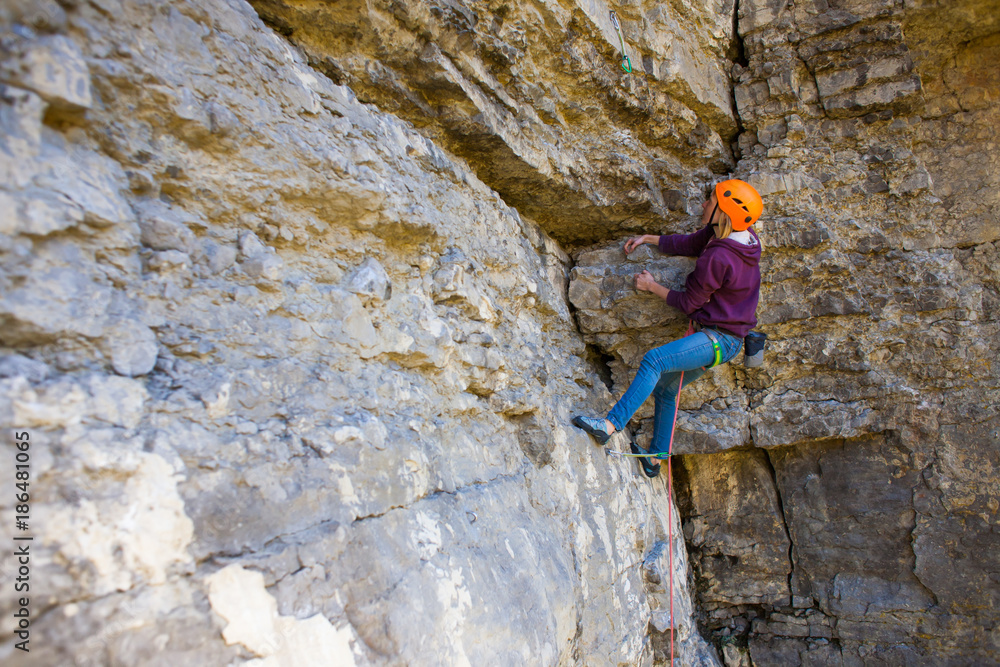 The woman in the helmet climbs the rock. The woman in the helmet climbs the rock.