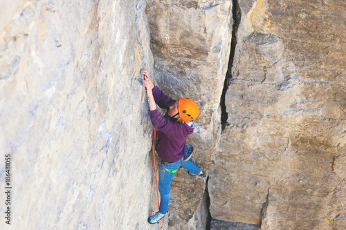 The woman in the helmet climbs the rock.