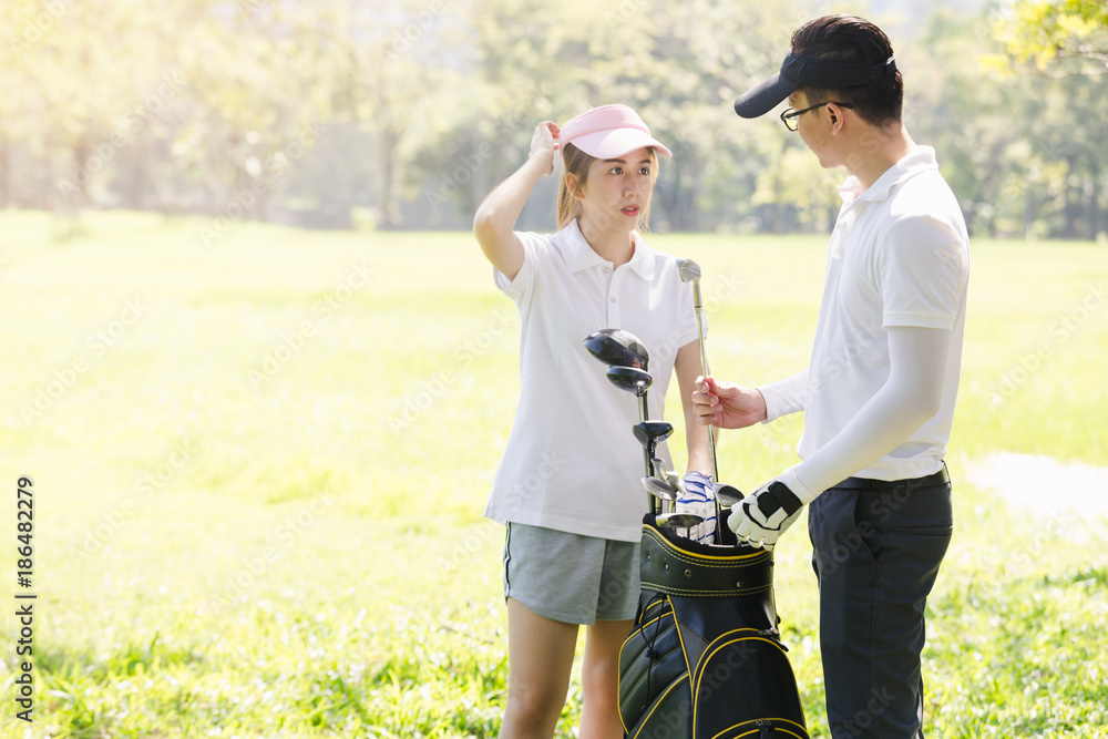 Asian couple playing golf. man teaching woman to play golf while standing on field