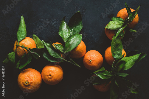 Tangerines or clementines with green leaf. Still life on dark background. Top view, toned image