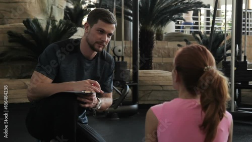 Personal fitness trainer makes up an individual training program for woman. Personal trainer will calculate optimal program and schedule for female client.