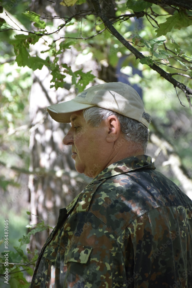 кавказский старик наслаждается тенью большого дуба в летнем лесу  