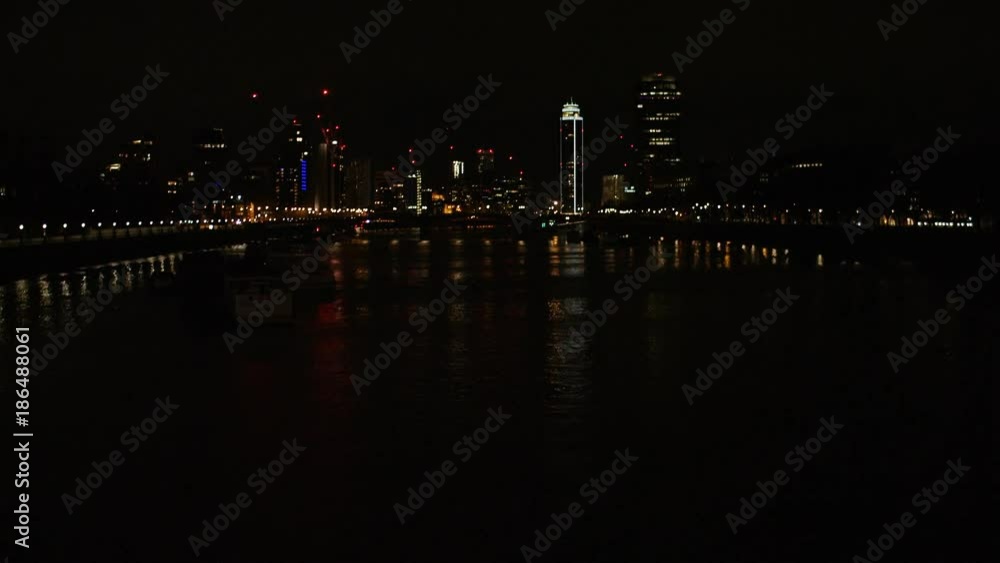 Camera tilts up from a river to see a city in the distance at night Camera tilts up from a river to see a city in the distance at night