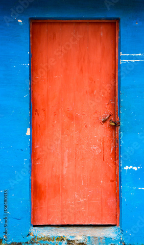 Red door on stained blue wall