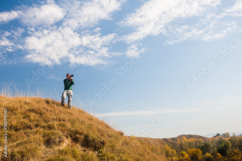Photographer taking photos in mountain on sunny day.  © djoronimo