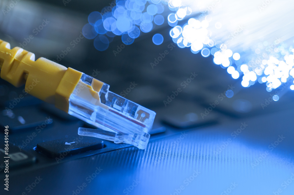 Yellow internet connection cable on laptop ,defocused optical fibre background. Yellow internet connection cable on laptop ,defocused optical fibre background.
