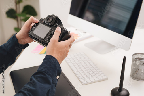 Male photographer, sitting at his desk, looking to camera