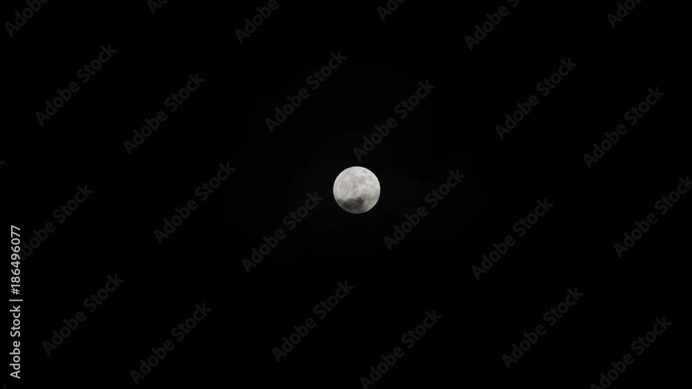 Dark clouds reveal a full bright moon in the middle of the screen Dark clouds reveal a full bright moon in the middle of the screen